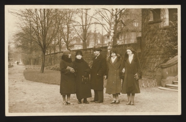 Front shows a group of five people (four women and one man in center) at the same park location as photo 0022/0023. This appears to be from the same birthday celebration, possibly taken the following month.