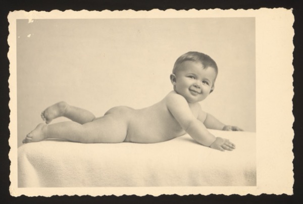 Front shows a baby lying on its stomach on a blanket, smiling. The child was approximately 10 months old when the photograph was taken.
