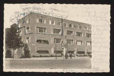 POSTCARD - APARTMENT BUILDING (front with handwritten annotations overlaid on image) Front annotations (German, partially legible): "Salon-Schlafz[immer]" (Living room / Bedroom) "Walters / Doris" (names — Walter's and Doris's rooms?) "3. Stock" (3rd floor) "v. [von] ... Terrasse" (from ... Terrace) Additional text on right margin (German, partially legible): "... am 5. mit dem ... Wohnung da. Platz ... d. St. Kuttscher in Gotha Versand..." Description: Photo shows a modern 1930s-era apartment building, three stories with ground floor shops, awnings, and balconies. A blue line is drawn on the image marking specific windows/apartment. The handwritten text identifies rooms and residents on the 3rd floor.