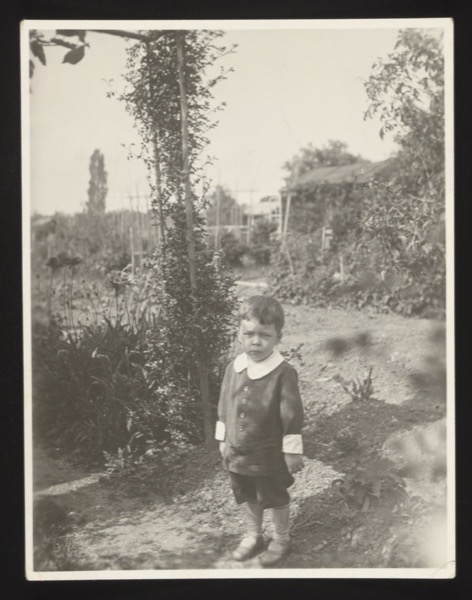 Front (0014) shows a small boy standing in a garden path with flowers and a greenhouse in the background. Same child as photo 0012/0013 (Walter), June 1930.