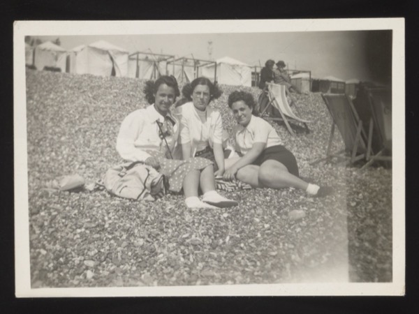 Front shows three women on a beach/shingle with buildings in the background — a typical Brighton seafront scene.